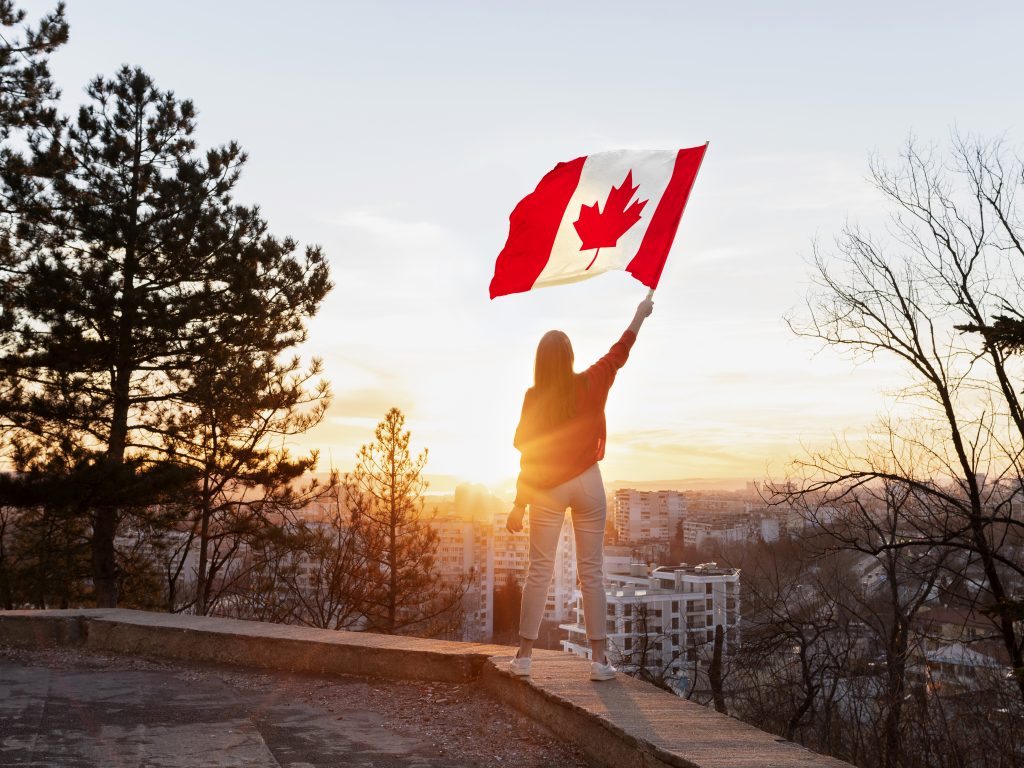 Woman waves a Canadian flag while looking over a city skyline